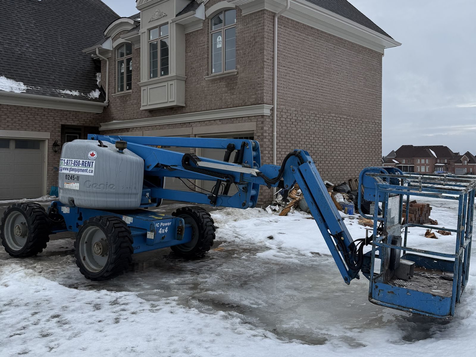 Genie articulating boom lift from GTA Equipment Rentals parked in the driveway of a two-storey brick home in the west GTA